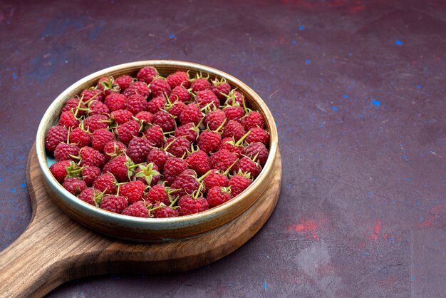 Vordere Ansicht frische rote Himbeeren reife Beeren auf dem dunkelblauen Hintergrund Beerenfrucht mildes Sommeressen