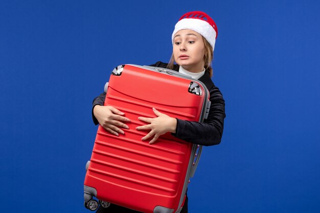 Vordere Ansicht junge Dame, die große rote Tasche auf blauer Wand Neujahrsferienreise trägt