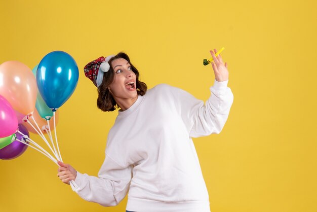 Vordere Ansicht junge Frau, die Ballons auf Gelb hält