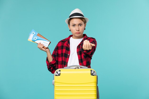 Vordere Ansicht junge Frau, die Brieftasche mit Tickets auf dem blauen Raum hält