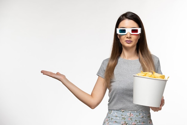 Vordere Ansicht junge Frau, die Chips hält, während Film in d Sonnenbrille auf hellweißer Oberfläche sieht