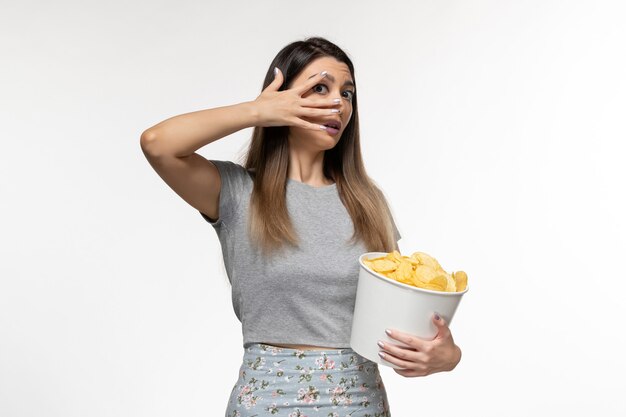 Vordere Ansicht junge Frau, die Kartoffelchips isst, die Film auf der hellen weißen Oberfläche sehen