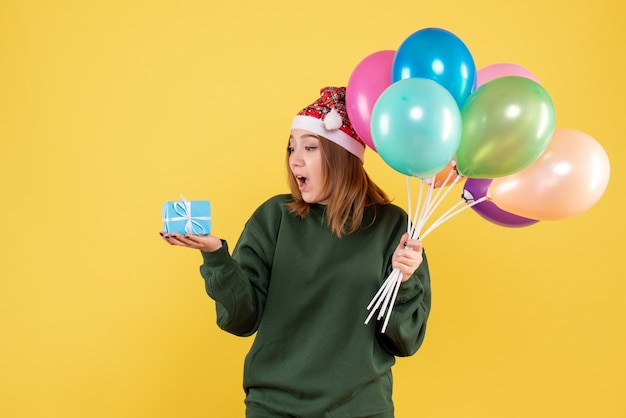 Vordere Ansicht junge Frau, die Luftballons und wenig Geschenk hält