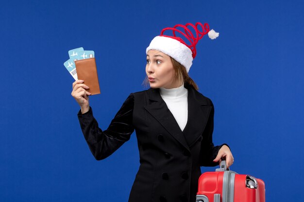 Vordere Ansicht junge Frau, die Tickets mit Tasche auf Feiertagsflugzeugferien des blauen Hintergrunds hält