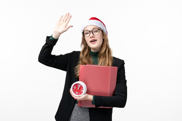 Vordere Ansicht junge Frau, die Uhr und Dateien auf weißer Wand College-Buchstunde hält