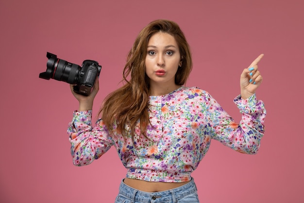 Kostenloses Foto vordere ansicht junge frau in blume entworfenes hemd und blaue jeans, die ein foto mit kamera auf dem rosa hintergrund machen