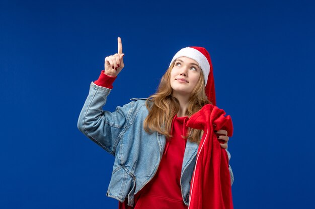 Vordere Ansicht junge weibliche Haltetasche mit Geschenken auf einem blauen Hintergrund feiert Weihnachtsemotion