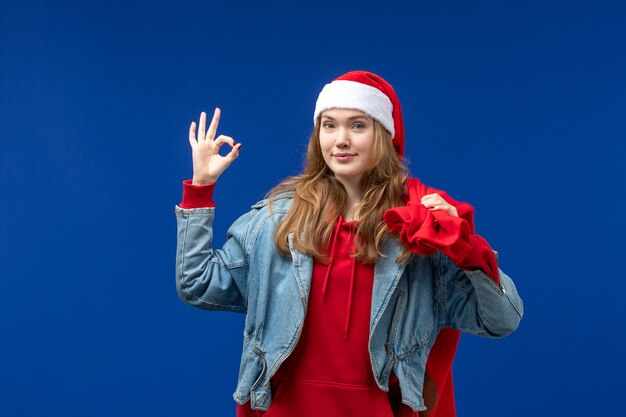 Vordere Ansicht junge weibliche Tragetasche voller Geschenke auf blauem Raum