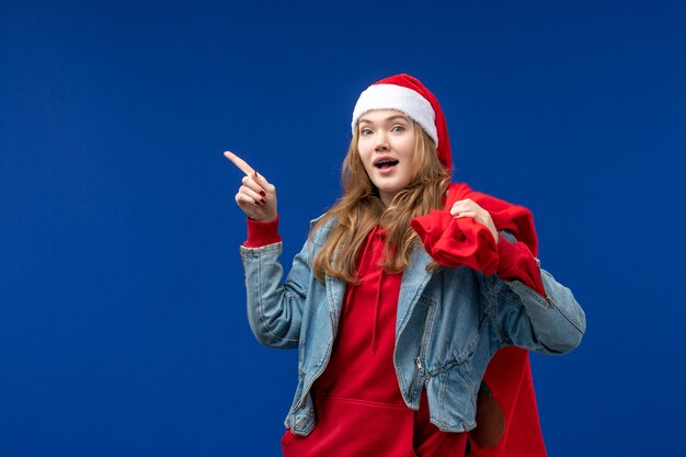 Vordere Ansicht junge weibliche Tragetasche voller Geschenke auf hellblauem Raum