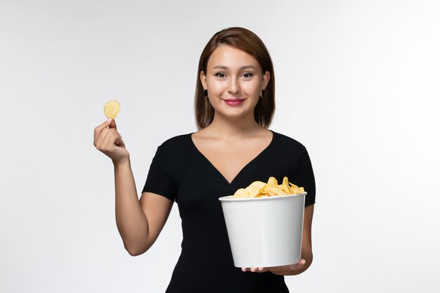 Vordere Ansicht junger weiblicher Haltekorb mit Kartoffelchips auf weißer Oberfläche