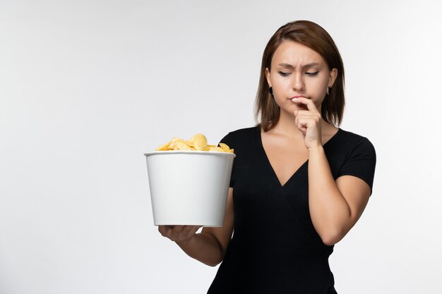 Vordere Ansicht junger weiblicher Haltekorb mit Kartoffelchips und Essen auf der hellweißen Oberfläche