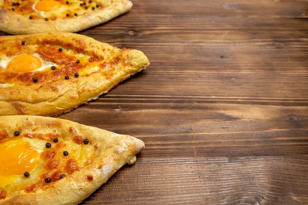 Vordere Nahansicht gebackene Eierbrote frisch aus dem Ofen auf braunem hölzernen Schreibtischteig-Eibrotbrötchenfrühstück