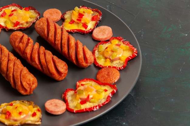 Vordere Nahansicht gekochte Paprika mit Würstchen innerhalb Platte auf dunkler Oberfläche