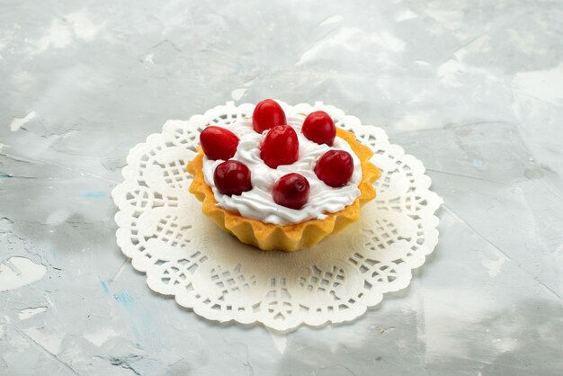 Vordere Nahansicht kleiner köstlicher Kuchen mit Sahne und roten Früchten auf der leichten Oberfläche süßer Tee