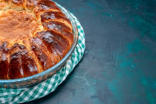 Vordere Nahansicht köstliche gebackene Kuchenrunde geformte süße innere Glaspfanne auf hellblauem Hintergrund.