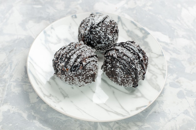 Vordere Nahansicht köstliche Schokoladenbällchen rund geformte Kuchen mit Zuckerguss auf dem hellweißen Schreibtisch backen Kuchen Schokoladenzuckerkuchen süß