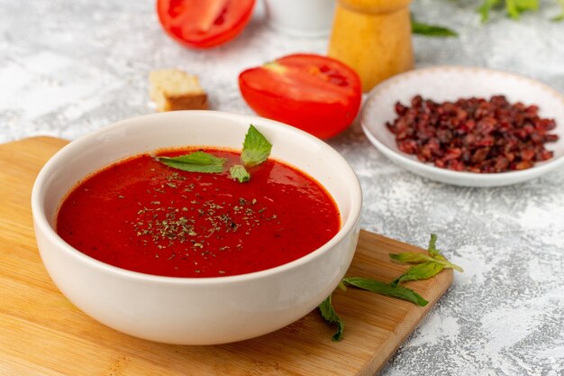 Vordere Nahansicht köstliche Tomatensuppe mit frischen roten Tomaten auf grauem Suppenmahlzeit-Abendessengemüse