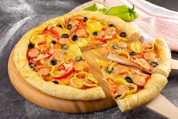 Vordere Nahansicht leckere käsige Pizza mit roten Tomaten, schwarzen Oliven, Paprika und Würstchen auf der grauen Oberfläche