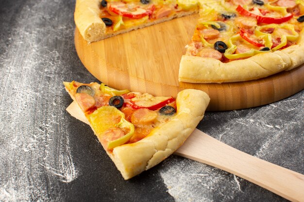 Vordere Nahansicht leckere käsige Pizza mit roten Tomaten, schwarzen Oliven, Paprika und Würstchen