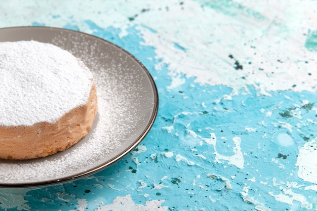 Vordere Nahansicht runder Kuchen mit Zuckerpulver innerhalb Platte auf hellblauer Oberfläche Kuchen backen Keks Zucker süße Tee Farbe