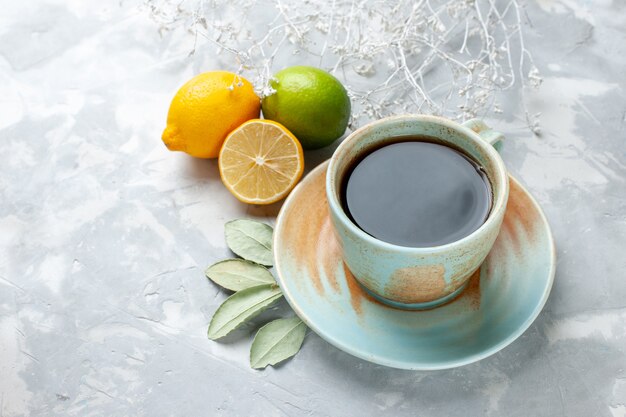 Vordere Nahansicht Tasse Tee mit frischen Zitronen auf dem weißen Schreibtisch Obst frische Zitrusfrüchte exotisch