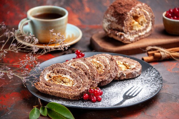 Vordere Nahansicht von Keksröllchen mit Tasse Tee auf dunkler Oberfläche