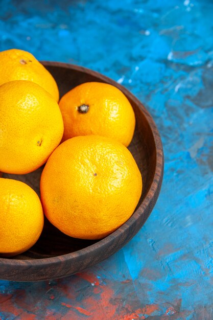 Vordere Nahaufnahme frische Mandarinen im Teller auf blauem Tisch