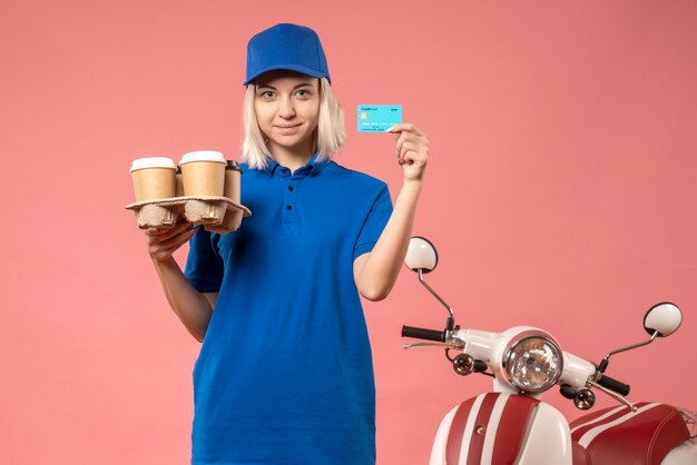 Vorderer Blick weiblicher Kurier mit Bankkarte und Lieferkaffee auf rosa Arbeitsdienstlieferung einheitliche Arbeitsfarbe