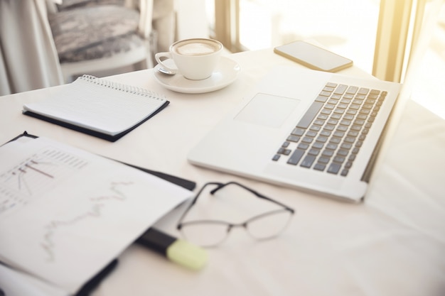 Vordergrund der Objekte am Arbeitsplatz: Brille, Diagramme, Laptop, Notebook