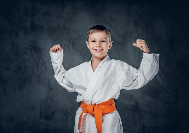 Vorschuljunge in einem weißen Karate-Kimono mit orangefarbenem Gürtel.