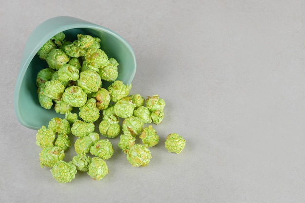 Kostenloses Foto vorspeisenschale umgefallen, grünes kandiertes popcorn auf marmortisch verschüttet.