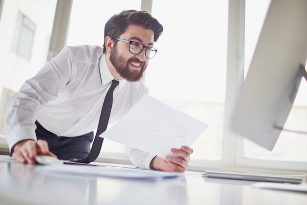 Vorstand mit einem Papier und Blick auf den Computer