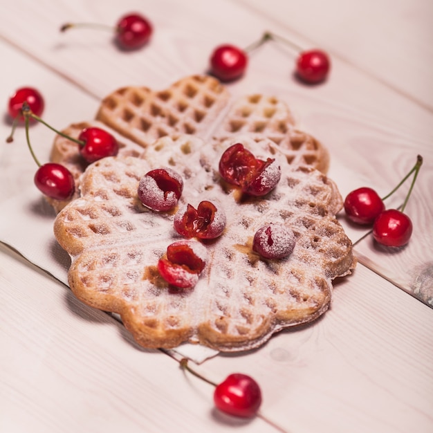 Waffeln mit Kirsche auf weißem Holzbrett