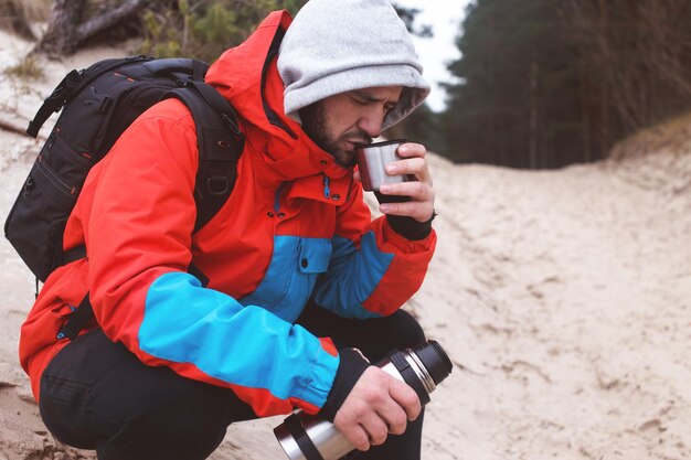 Wanderer, der auf dem Sand sitzt und sich erholt