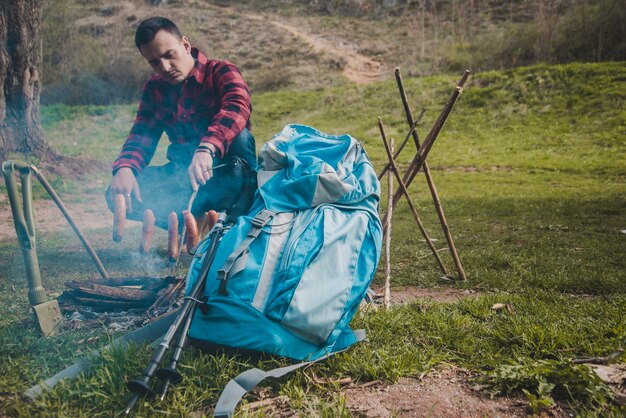 Wanderer, der Wurst am Lagerfeuer vorbereitet