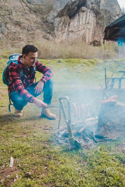 Wanderer durch das Feuer, das Würste vorbereitet