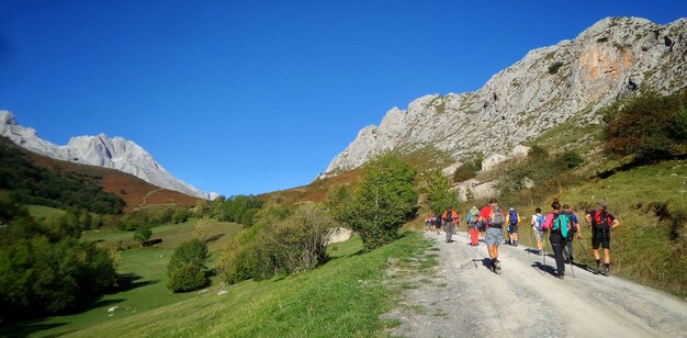 Wanderer gehen durch einen Weg, der von grünen Hügeln im Sonnenlicht umgeben ist