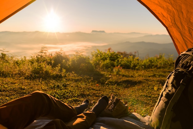 Wanderer-Mann, der in einem touristischen Zelt durch Reise-Entdeckungs-Konzept sitzt