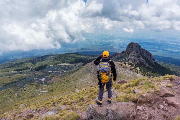 Kostenloses Foto wanderer mit einem rucksack, der auf dem gipfel des berges steht