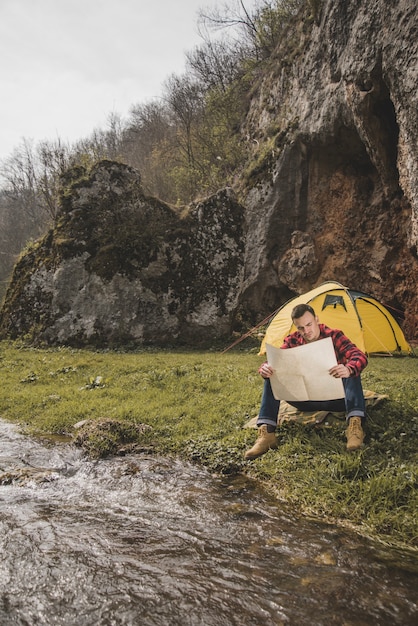 Wanderer mit Karte sitzt neben dem Fluss