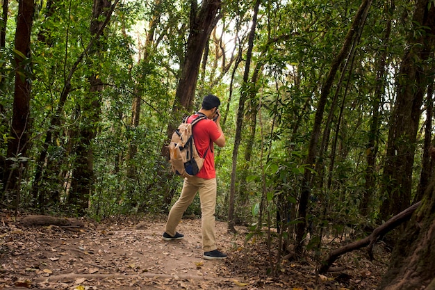 Wanderer mit Rucksack, der ein Foto im Wald nimmt