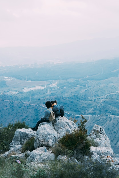 Kostenloses Foto wanderer sitzen auf einem felsen