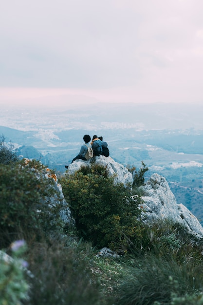 Kostenloses Foto wanderer sitzen auf einem felsen