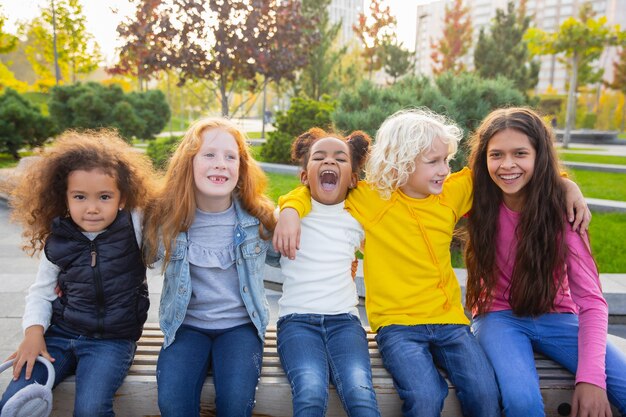 Warm. Interracial Gruppe von Kindern, Mädchen und Jungen, die zusammen im Park am Sommertag spielen.