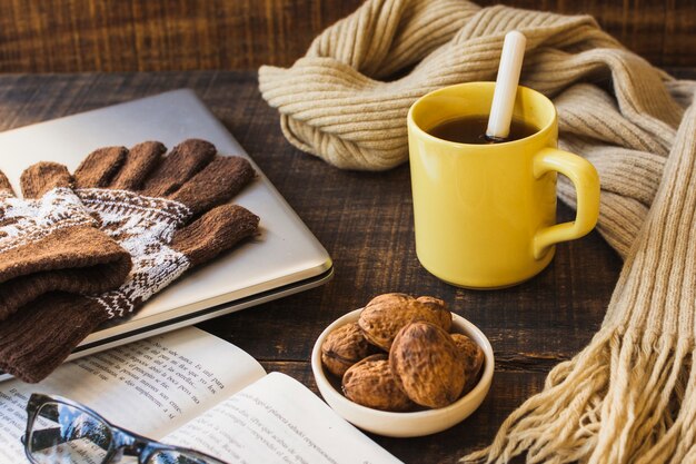 Warme Kleidung und Snacks in der Nähe von Laptop und Buch