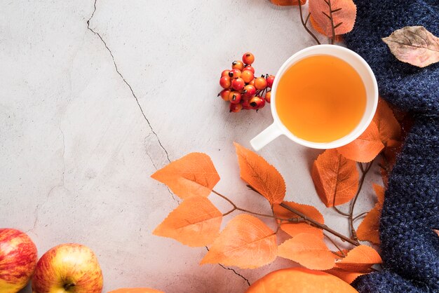 Warmer Tee und Herbstlaub auf rissiger Oberfläche