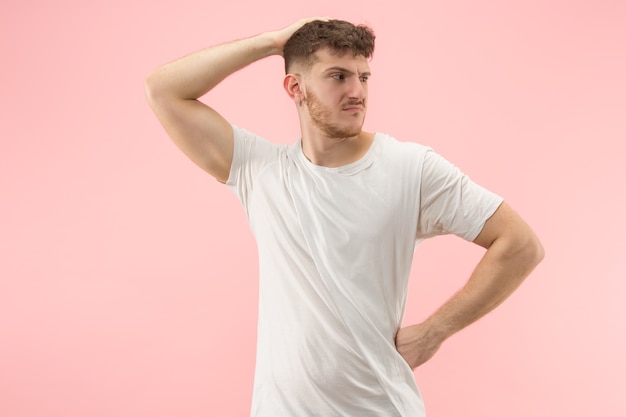 Warum ist das so. Schönes männliches halblanges Porträt lokalisiert auf trendigem rosa Hintergrund. Junger emotional überraschter, frustrierter und verwirrter Mann