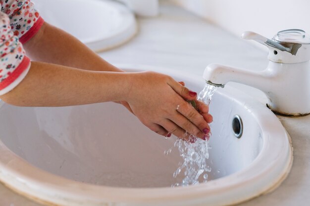 Waschende Hand des Mädchens im Waschbecken