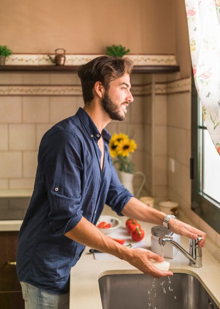 Waschender weißer Rettich des jungen Mannes in der Wanne