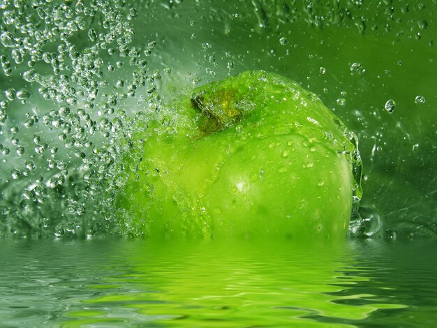 Wasser spritzt auf einem grünen Apfel
